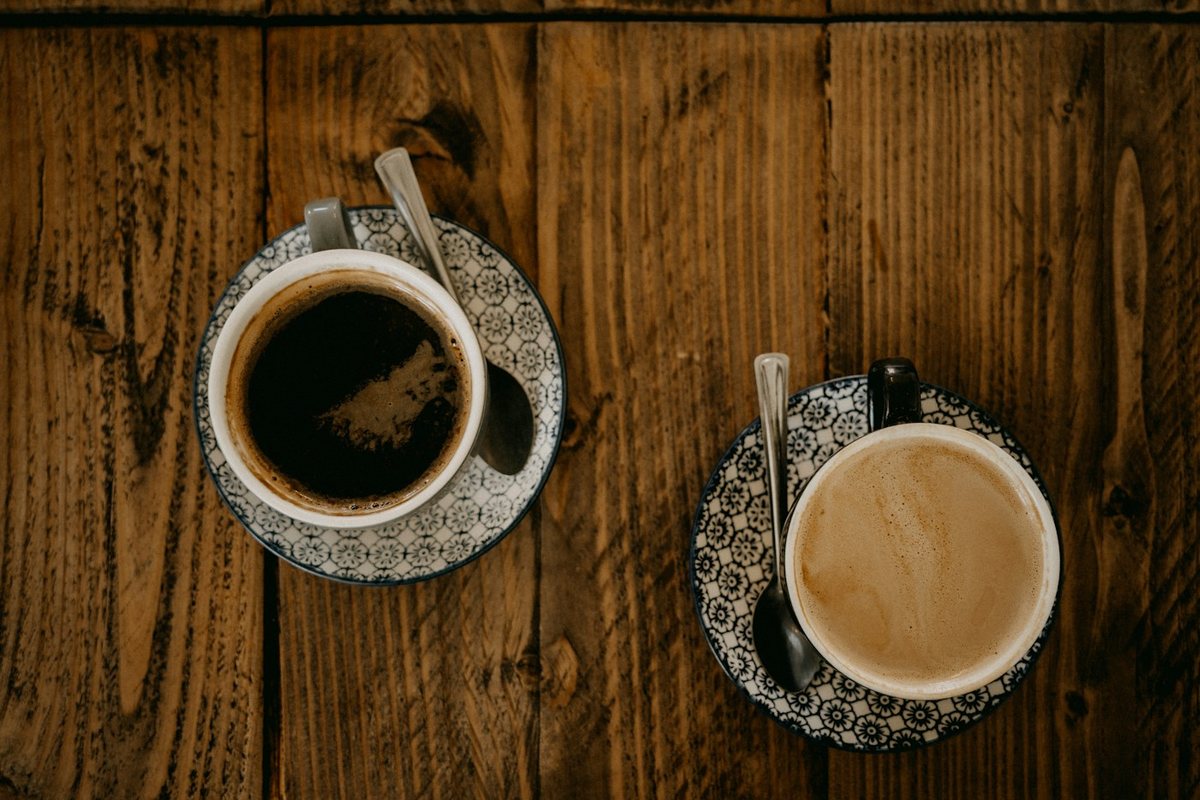 Two patterned coffee cups and saucers on a wooden table
