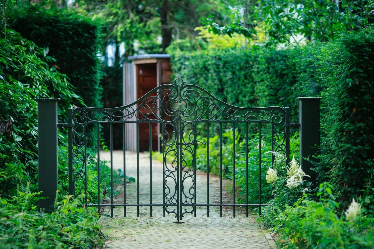 a gate in the middle of a lush green garden