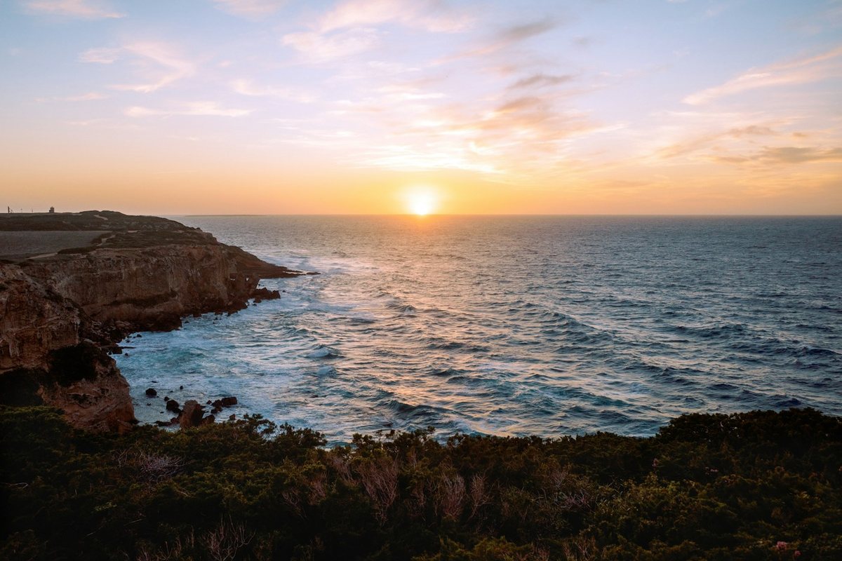 Sunset over the ocean viewed from a coastal cliff