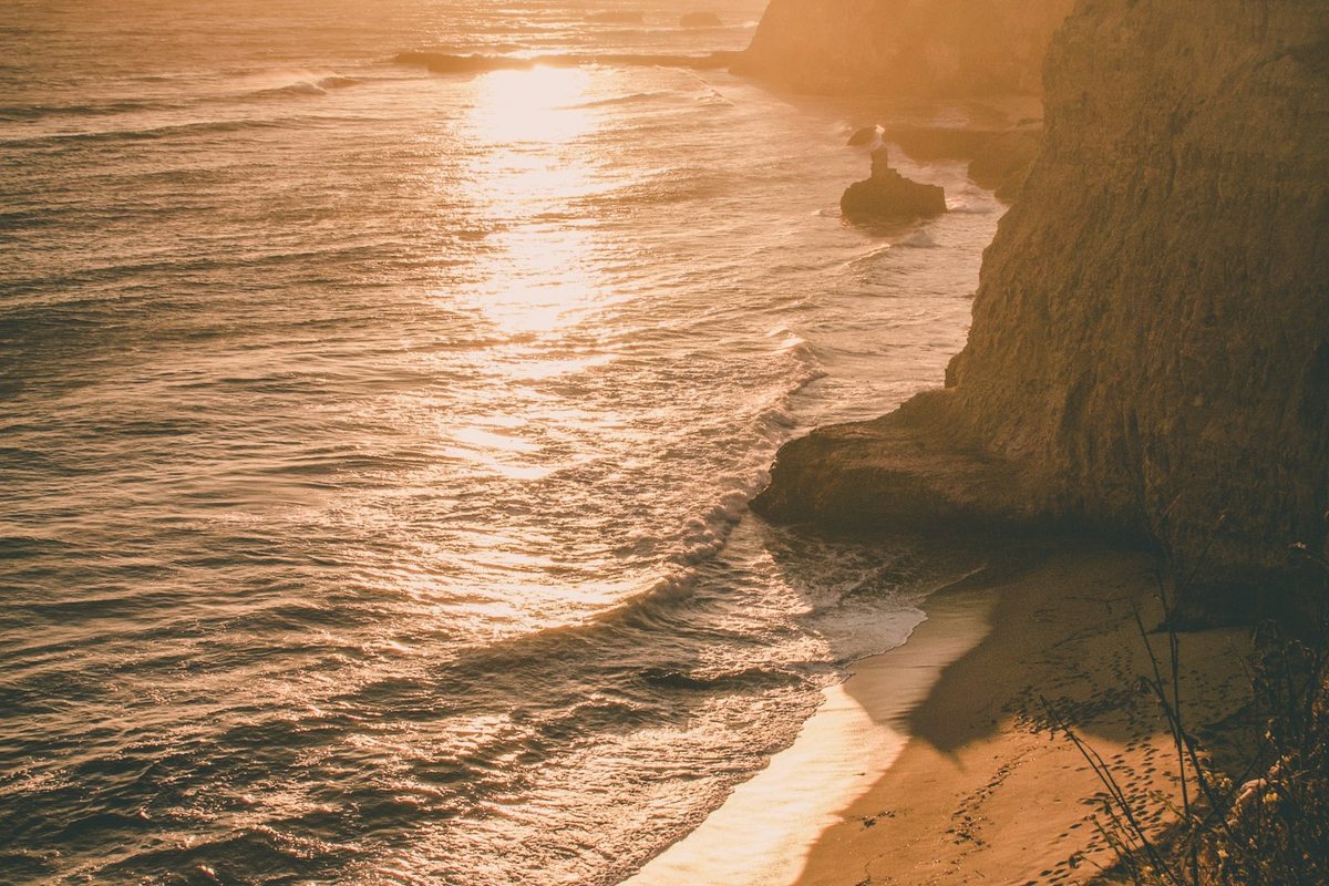 the sun is setting over the water at the beach