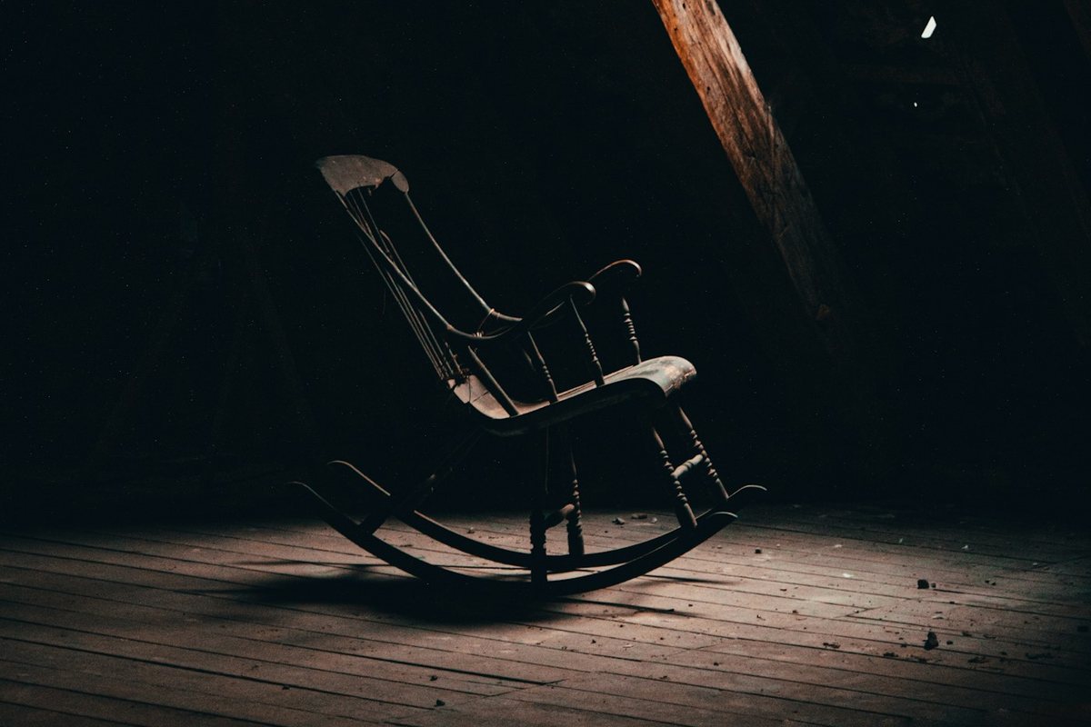 a rocking chair on a wooden floor in a dark room