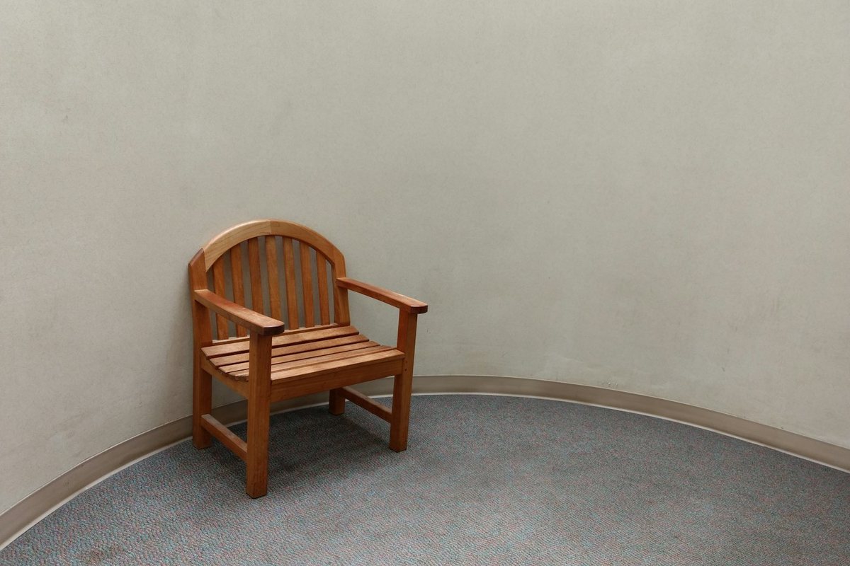 Vacant brown wooden armchair beside a plain wall